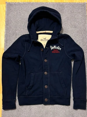 Vintage Hollister Cardigan Med Knappar - Säljer denna otroliga sällsynta och feta Hollister cardigan med knappar | Mycket bra skick | Längd ≈ 65cm, Bredd armhåla - armhåla ≈52cm | Modell 175, 68 kg