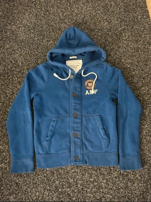 Abercrombie & Fitch Hoodie - Super snygg och stilren Abercrombie hoodie med knappar. Den är storlek M men passar även S, är i fint skick. Hör av dig vid frågor eller funderingar. 