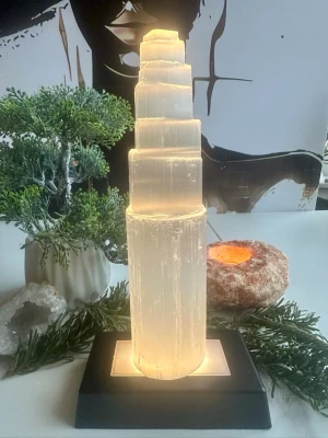 Handskuret selenittorn på 20 cm.  -  Selenit är känd för sina renande och balanserande energier – perfekt för meditation, vila eller som stämningsfull inredningsdetalj. Placera det i sovrummet, vardagsrummet eller ditt heliga hörn för en känsla av klarhet och stillhet.   Vikt ca 650 gram.   Alla kristaller och ädelstenar jag lägger upp här är egenimporterade för att garantera äkthet. 