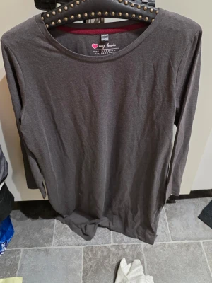 Mörkgrå långärmad klänning bpc - En enkel och stilren mörkgrå klänning från bpc bonprix collection. Klänningen har rund halsringning och långa ärmar, tillverkad i mjukt material som känns skönt mot huden. Perfekt för dig som gillar en avslappnad och klassisk look.