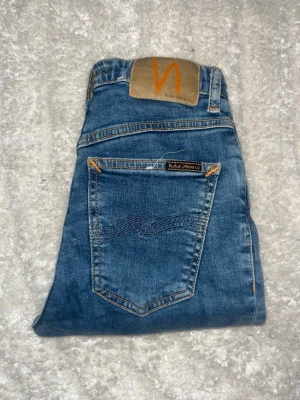 Nudie jeans - Ett par snygga blåa skinny jeans från Nuie Jeans. Midja 28cm, längd 93cm. Obs jeansens benslut är avklippta, så kolla måtten. JAG SKICKAR EJ FLER BILDER NÄR JAG BÄR JEANSEN! för bättre inblick i passformen rekommenderar jag att googla på modellnamnet. För storleksguide kolla måtten noggrant då jeansen alltid kan vara uppsydda heller krympta och jag ej tar emot returer :) s6,4