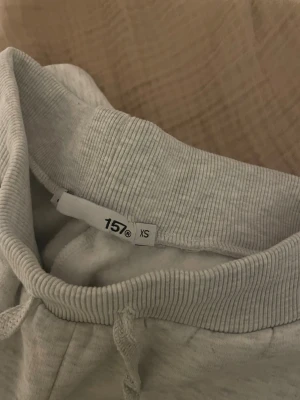 Ljusgrå mjukisbyxor från 157 - Säljer ett par ljusgrå mjukisbyxor från 157 i storlek XS. Byxorna har resår och dragsko i midjan samt två sidofickor. Tillverkade i mjukt och bekvämt material, perfekta för chill dagar. Klassisk rak passform och ribbade muddar vid midjan. Aldrig använt den bara testat en gång 
