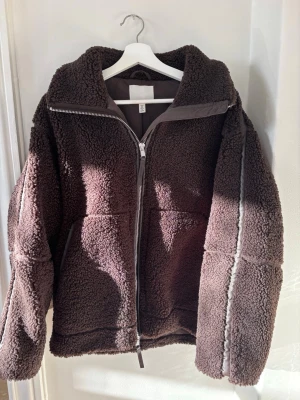 Brun teddyjacka från H&M - Mysig brun teddyjacka från H&M med dragkedja framtill och är i strl  S. Trendig och perfekt nu till början av våren!