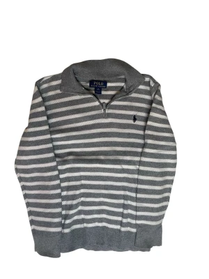 Gråvit randig tröja Polo Ralph Lauren - Snygg grå och vit randig tröja från Polo Ralph Lauren med halv dragkedja och klassisk krage. Tröjan har lång ärm och broderad logga på bröstet. Perfekt för en avslappnad men stilren look.