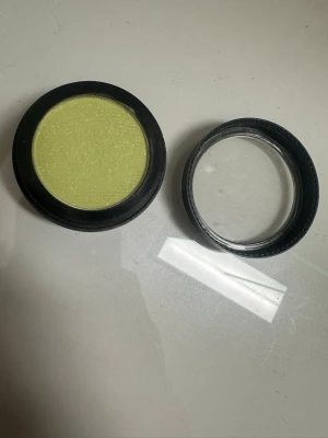 Ljusgul skimrig ögonskugga - En rund ögonskugga i en fräsch ljusgul nyans med skimrande finish. Kommer i en svart plastförpackning med genomskinligt lock. Perfekt för dig som vill addera en pop av färg till din sminkning.