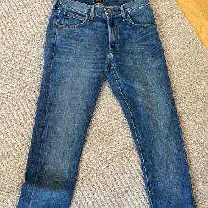 Blå slim fit jeans  - Snygga blå slim fit jeans med klassisk femficksdesign och normalhög midja. Jeansen har en lätt tvättad look och raka ben. Perfekta för en avslappnad stil och passar till det mesta. Materialet är mjukt denim i bomull.