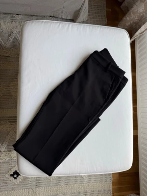 Svarta kostymbyxor från Bikbok - Snygga svarta kostymbyxor med klassiskt snitt och pressveck. Byxorna har hällor för bälte och raka ben. Perfekta för en stilren look och passar till många olika outfits.