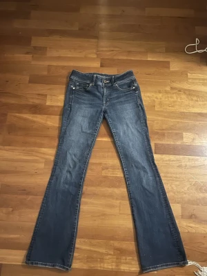 Blå bootcut jeans  - Säljer ett par klassiska blå bootcut jeans från American eagle med stilrena detaljer på bakfickorna. Lågmidjade och stretchiga så de passar både M och S, men är lite för stora i midjan för mig, passar dig som är ungefär 170 men man kan ju såklart vika upp eller sy oxå☺️. (Säljs inte längre) kan även fixa en bild när de sitter på! Bud går oxå bra!