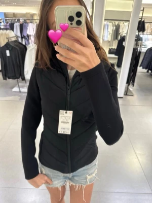 Svart vindjacka från Zara  - Snygg svart vindjacka med hel dragkedja framtill och figurnära passform. Jackan har en stilren design utan synliga loggor och är perfekt för en sportig look. Materialet är lätt och smidigt, vilket gör den enkel att bära till vardags. Jackan är från Zara❤️ köpt för 400