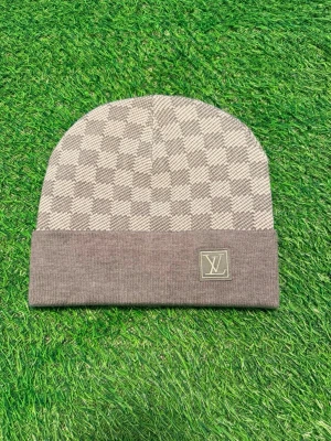 Grå Louise Vuitton mössa med rutmönster - Snygg grå mössa från Louise Vuitton med klassiskt rutmönster och vikt kant. På kanten sitter en patch med L.V-loggan. Perfekt accessoar för dig som vill ha en exklusiv och stilren look. Materialet ser ut att vara mjukt och bekvämt, troligen bomull eller ullmix.