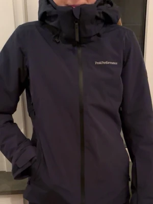 Mörkblå vindjacka Peak Performance - Snygg mörkblå skidjacka från Peak Performance  med huva och hel dragkedja framtill. I storlek S. Använd fåtal gånger 💙