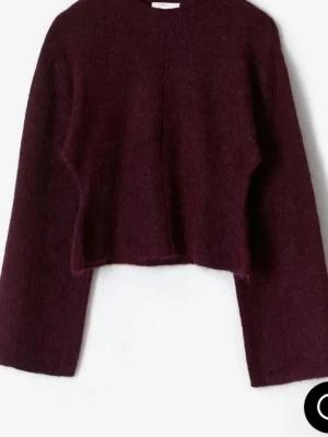 Vinröd stickad tröja - Mysig vinröd stickad tröja med croppad passform och vida ärmar. Tröjan har rund halsringning och är tillverkad i ett fluffigt material som ger en trendig look. Perfekt för dig som vill ha en statement-piece i garderoben.