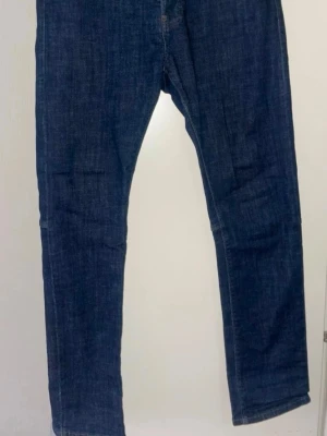 Mörkblå Dsquared2 ICON jeans - Säljer ett par mörkblå jeans från Dsquared2 med ICON-tryck på bakfickan. 