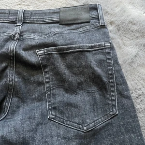 Svarta tapered jeans från Jack & Jones - Snygga svarta jeans från Jack & Jones | Nypris 899kr | strl 32 32 men passar nog bäst i lite mindre storlek eftersom den har tvättats fåtal gånger | Jeansen är använda några gånger men inte några defekter alls | Modellen är jjmike vilket då är en Tapered Jeans modell.