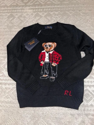 Polo Ralph Lauren Bear tröja svart – Ny med tag – Herr XS - Säljer denna Svarta Ralph Lauren tröja med Björn som design. Den är storlek S men kan möjligt passa XS beroende på dig. Skulle säga att den är liten i storlek.