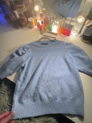 Ljusblå stickad tröja Vero Moda XS - Supersöt ljusblå stickad tröja från Vero Moda i storlek XS. Tröjan har puffiga axlar, ribbade muddar och en klassisk rund halsringning. Perfekt för dig som vill ha en mysig och stilren look till hösten eller vintern.