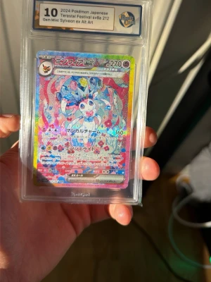 Ingen väst på bilderna - Bilderna visar ett Pokémonkort (Sylveon ex Alt Art) i ett graderat plastfodral, inte en väst. Ingen information om väst finns att beskriva.