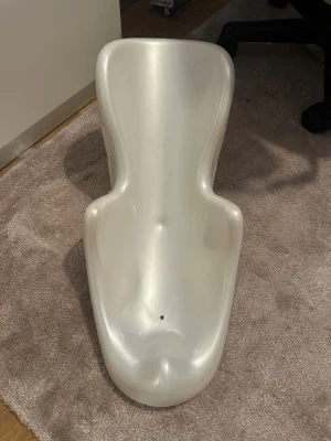 Vit badstol för baby i plast - Praktisk vit badstol för baby i hård plast. Ergonomisk form med stöd för rygg och armar samt sugproppar undertill för att fästa i badkaret. Perfekt för att göra badstunden enklare och säkrare för små barn.