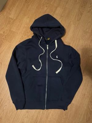 Ralph lauren hoodie - Säljer en sprillans ny ralph lauren hoodie, helt oanvänd i helt nytt skick i storlek S. Koftan är egentlihen i storlek M men den är liten i modell och passag bättre i storlek S. Vid fler bilder eller frågor är det bara att höra av sig🙌