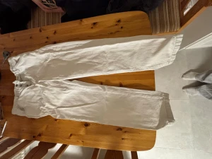 Vita raka jeans från Zara - Säljer ett par vita jeans från Zara med rak passform och klassisk knappgylf. Byxorna är tillverkade i bomull och har en clean look som passar till det mesta. Perfekta för dig som gillar stilrena och ljusa outfits.