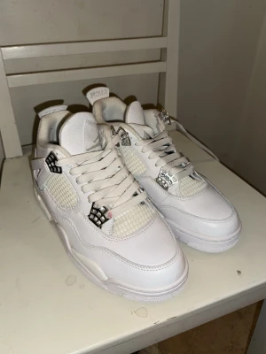 Vita nice Fordan 4 sneakers - Säljer ett par fräscha vita nice Fordan 4 sneakers pure money med coola silverdetaljer och meshpaneler på sidorna. Skorna har snörning, rund tå och platt sula. Perfekta för dig som vill ha en clean och stilren look med klassisk streetwear-vibe. finns Chans att dom är fa-k-e