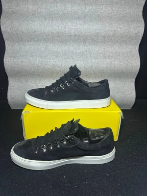 Diemme skor - Stilrena svarta sneakers från Diemme med låg profil och vit platt sula. Skorna har snörning med metallöglor och är tillverkade i mocka för en mjuk känsla och är i storlek 42. Perfekta för dig som gillar enkel och modern design. Orginalbox medföljer! ✅