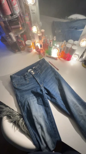 Blå bootcut jeans med dubbla knappar - Snygga blå skinny jeans med dubbla knappar i midjan och klassiska fickor fram. Jeansen har en ljus tvätt och smal passform som sitter tight hela vägen ner. Perfekta till en avslappnad look och funkar till det mesta.