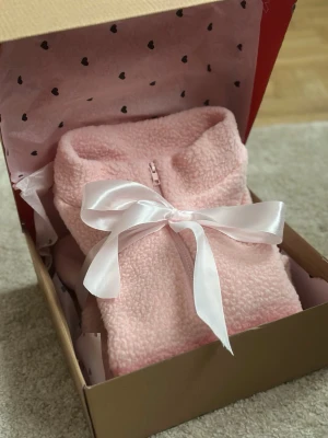 Rosa teddytröja med halv dragkedja - Supermjuk och fluffig rosa teddytröja med halv dragkedja och hög krage. Perfekt för mysiga hemmakvällar eller chill dagar. Tröjan har en relaxed fit och är gjord i ett fleece-liknande material som känns extra gosigt.