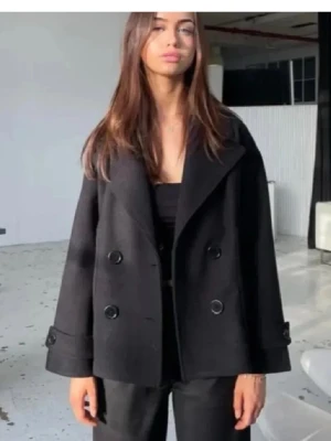 Svart dubbelknäppt rock - Snygg svart kappa från design by si. Den har långa ärmar och passar perfekt på vår/höst. Det förekommer ett mini hål i inner tyget i axeln, men inget som märks när man har den på sig!💓