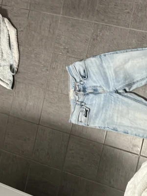 Ljusblå bootcut jeans med medelhög midja - Snygga ljusblå jeans med bootcut-modell och medelhög midja. Jeansen har klassisk femficksdesign och är tillverkade i ett mjukt denimtyg. Perfekta för dig som gillar en retroinspirerad look med utsvängda ben.