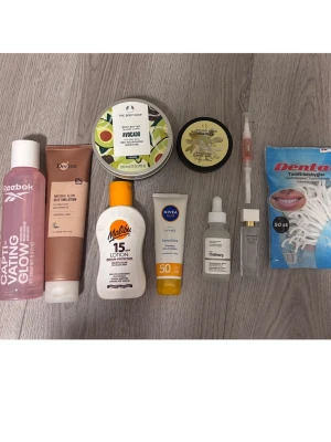Hudvårds- och skönhetspaket mix - Ett blandat paket med hudvårds- och skönhetsprodukter, inklusive body butter med avokado och morgondoft från The Body Shop, solkräm från Nivea och Malibu, ansiktsserum från The Ordinary, brun utan sol, tandtråd och ansiktsmist. Perfekt för dig som vill ha en komplett skönhetsrutin.
