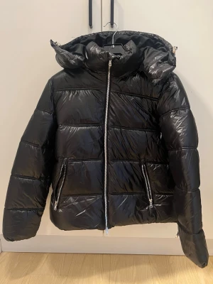 Svart pufferjacka lager 157 - Snygg svart pufferjacka med glansig finish, jackan är från lager 157 och är helt oanvänd, storlek xs men mer åt s/m hållet 