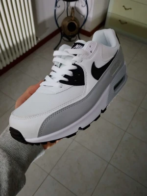 Nike Air Max vita och svarta sneakers - Nike sopiga Air Max sneakers i vitt och svart med klassisk swoosh på sidan. Skon har snörning, mesh och syntetmaterial, samt en chunky sula med synlig Air-enhet. Perfekt för dig som vill ha en clean och sportig look.