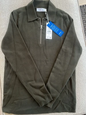 Olivgrön halvzip-tröja från Samsoe - Snygg olivgrön långärmad tröja från Samsoe Samsoe med halv dragkedja och klassisk krage. Tillverkad i mjukt material med LENZING EcoVero viskos för en skön känsla. Perfekt till jeans eller chinos för en clean look. Säljer för 950kr orginalpris 1400kr, anledning för liten för mig. 