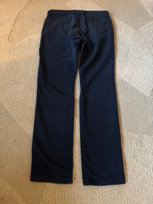 Mörkblå chinos från Vans chinos stlk 30 - Snygga mörkblå chinos från Vans med raka ben och klassisk passform. Byxorna har sidofickor fram och två bakfickor med knapp. Tillverkade i mjuk bomull med en stilren look som passar till det mesta. Stlk 30