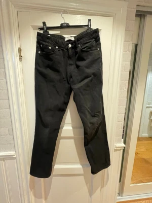 Svarta straight jeans Only & Sons - Svarta jeans från Only & Sons i modellen Edge Straight. Klassisk femficksdesign, raka ben och normal passform. Jeansen har silverfärgade nitar och knapp, samt en diskret logga bak i midjan. Tillverkade i bomull för en skön känsla.