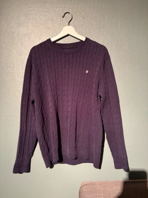 Mörkblå kabelstickad tröja Bondelid M - Säljer en mörkblå  kabelstickad tröja från Bondelid i storlek M. Tröjan har rund hals, lång ärm och ett diskret Bondelid-märke på bröstet. Perfekt för dig som gillar klassisk stil med en twist. Materialet är mjukt och känns riktigt skönt mot huden.