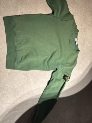 Stone Island sweater -  En riktigt Härlig mörkgrön sweater från Stone Island. Junior skulle påstå att Den passar ungefär 11 till 12 åring Dock finns det ett litet hål i armen, men går lätt att sy 