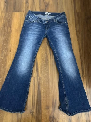 Blå bootcut jeans från 157, stl L - Säljer ett par blå bootcut jeans från 157 i storlek L, short längd. Jeansen har klassisk femficksdesign, snygg slitning framtill och breda ben som ger en retrovibe. Tillverkade i jeansmaterial med skön passform.