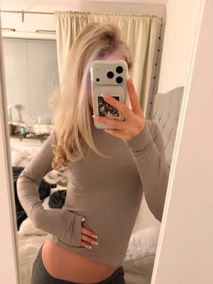 Beige långärmad topp i stretch - Säljer en enkel och stilren beige långärmad topp i mjukt stretchigt material. Modellen är figurnära med långa ärmar och rund halsringning. Perfekt att styla med jeans eller kjol för en clean look.