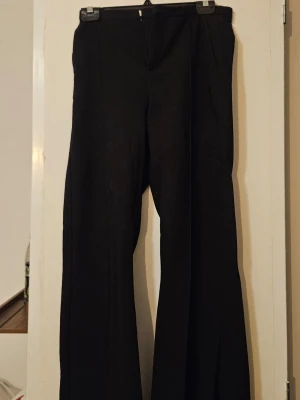 Svarta kostymbyxor - Stilrena svarta kostymbyxor med vida ben och pressveck. Klassisk passform med fickor i sidorna. Perfekta för en dressad look och passar till många olika outfits.
