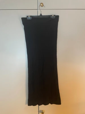 Svart ribbad långkjol Gina Tricot - Säljer en svart ribbad långkjol från Gina Tricot. Kjolen har en rak passform och är tillverkad i ett mjukt, stretchigt material som sitter snyggt på kroppen. Perfekt att styla med en enkel topp eller hoodie. Nästan aldrig används!!💞💞