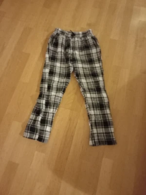 Pyjamasbyxor Kappahl 146/152 - Säljer ett par svartvita rutiga pyjamasbyxor från Kappahl i storlek 146/152. Byxorna har resår i midjan och är gjorda i mjukt bomullstyg, perfekta för chill dagar hemma. Klassisk rutig design som alltid funkar.