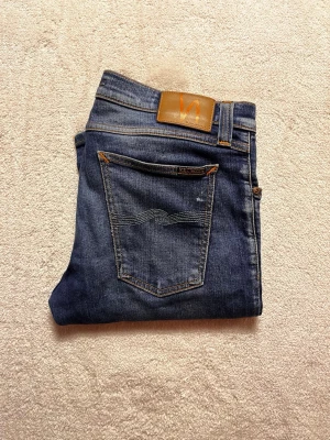 Nudie Jeans Slim Fit 33/34 - Hej! Säljer nu mina Nudie Jeans. De är riktigt snygga. Passformen är slim fit. Jeansen är i storlek 31/34 men sitter mer som 33/34.  Midjemått: 42 cm. Längd: 109 cm. Hör av dig om du undrar något!