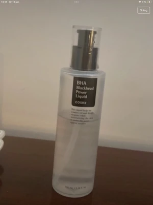 COSRX BHA Blackhead Power Liquid - COSRX BHA Blackhead Power Liquid är en genomskinlig toner i plastflaska med pump. Innehåller BHA som hjälper till att ta bort pormaskar, kontrollera överflödig olja och återfukta huden. Flaskan rymmer 100 ml och har svart etikett med vit text.