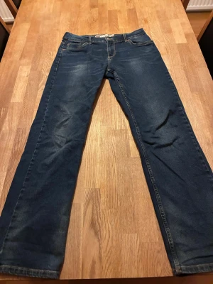 Levi's 551 straight jeans blå - Säljer ett par klassiska Levi's 551 straight jeans i mörkblå denim. De har raka ben, fem fickor och snygga slitningar framtill. Typisk Levi's-lapp bak i som är lite trasig. 