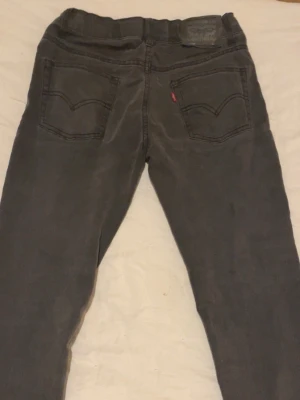 Levi's  mörkgråa jeans - Säljer ett par grå Levi's 512 jeans med skinny fit. Klassisk femficksmodell, svarta sömmar och röd Levi's-tag på bakfickan. Jeansen är i stretchigt denim och har en smal passform som sitter tajt längs benen.