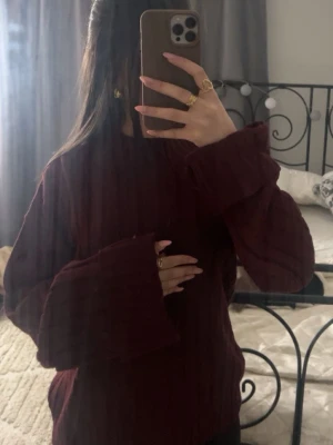 Vinröd stickad tröja med vida ärmar - Mysig vinröd stickad tröja med breda, långa ärmar och ribbat mönster. Perfekt för dig som gillar oversized känsla och vill ha något riktigt bekvämt och snyggt till höst och vinter.