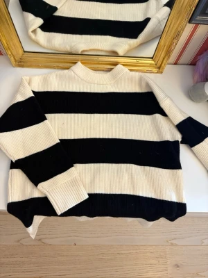 Randig stickad tröja  -  ribbstickad tröja från Zara med breda svarta och vita ränder. Tröjan har lång ärm, rund halsringning och är i mjukt stickat material.