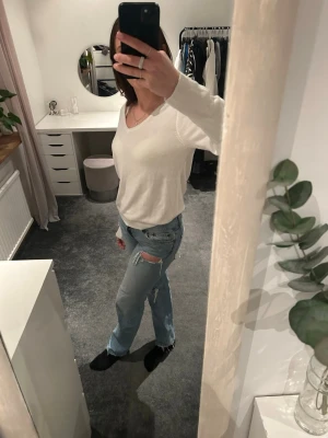 Vit v-ringad stickad tröja - Säljer en enkel och stilren vit stickad tröja med v-ringning och långa ärmar. Tröjan har en mjuk och tunn känsla, perfekt att bära till jeans eller kjol. Passformen är normal och den är lätt att matcha med olika outfits.